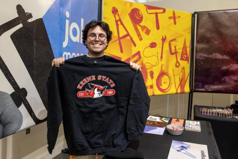A graphic dsign student holding their design